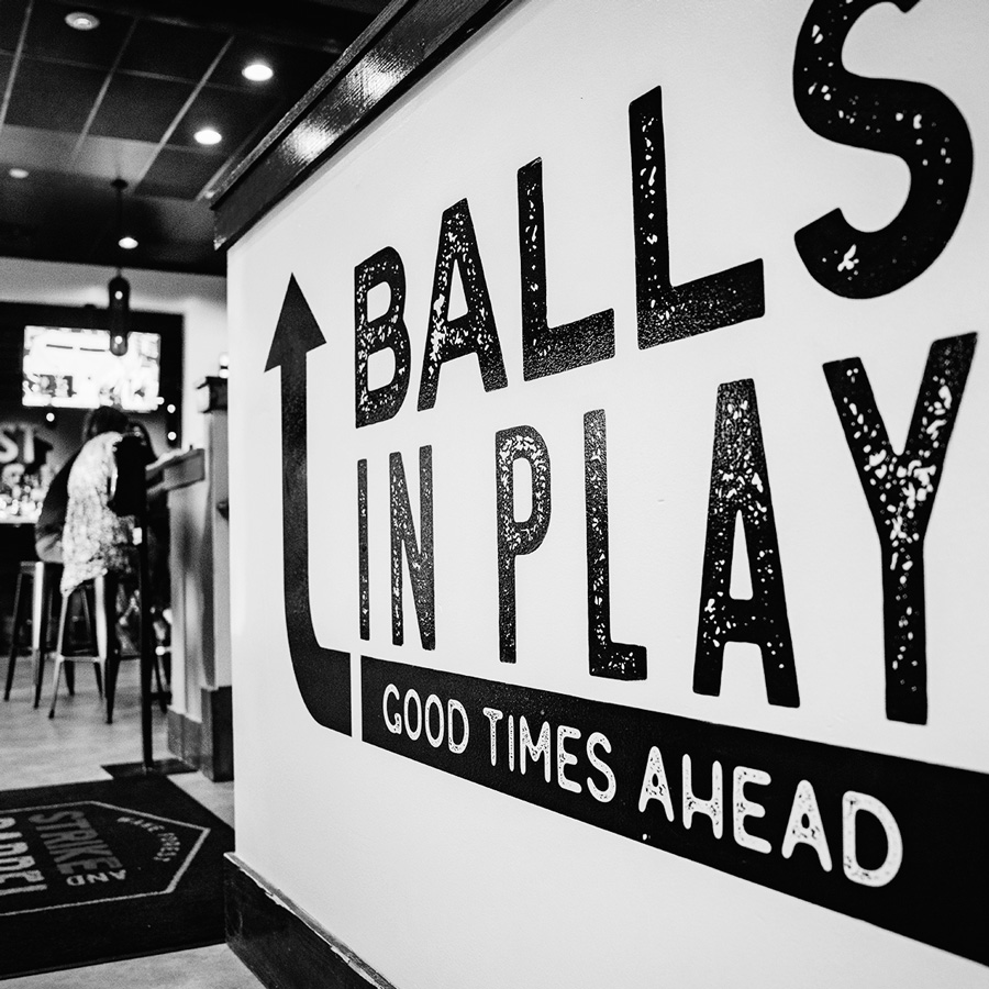 Balls in play lettering mural on a wall with an arrow pointing forward